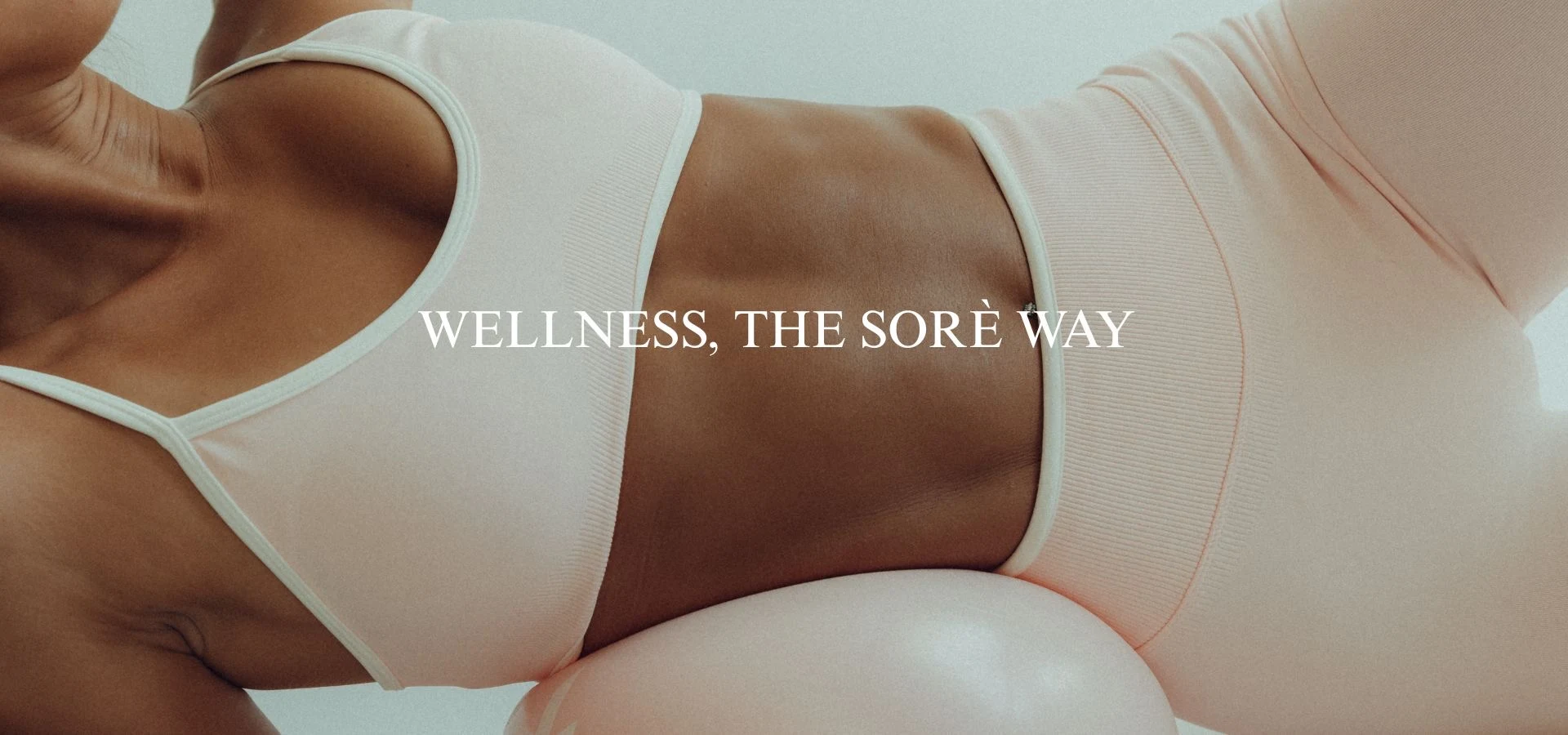 Woman in pale activewear with a Pilates ball. Wellness, the Sorè way.